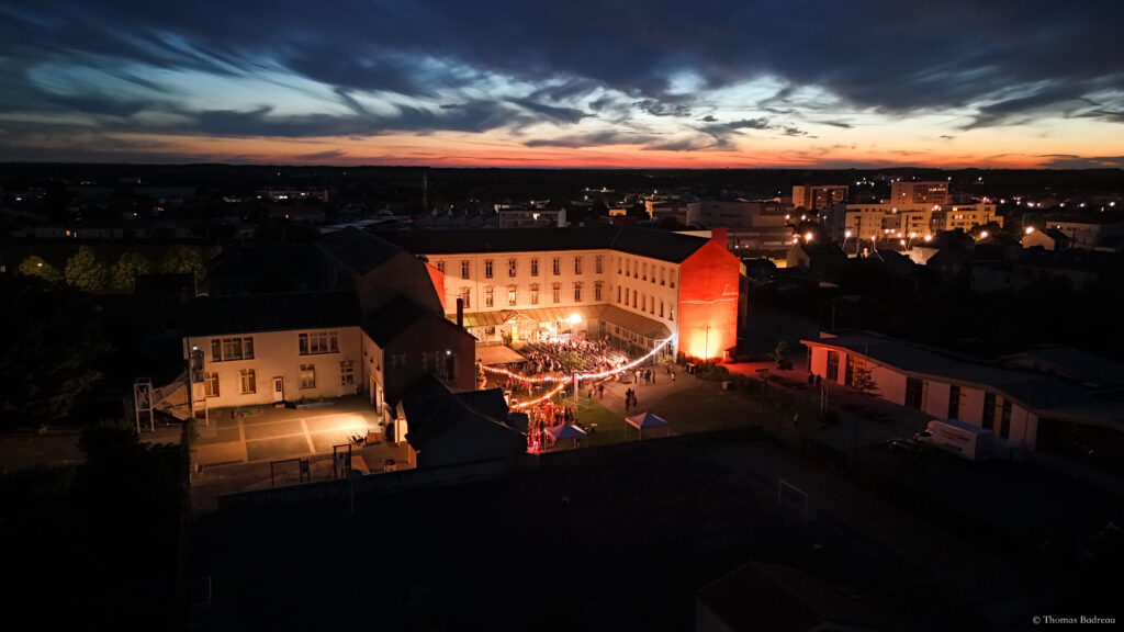 photo d'une école pris du ciel à la tombé de la nuit montrant des installations scèniques