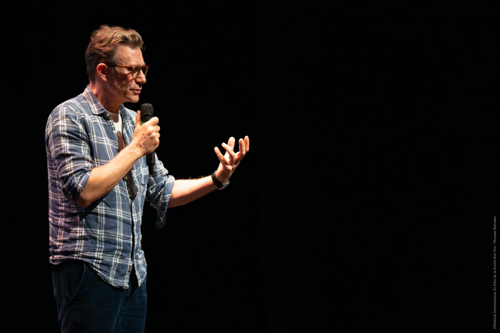 photo de Michel Hazanavicius qui parle au micro sur fond noir
